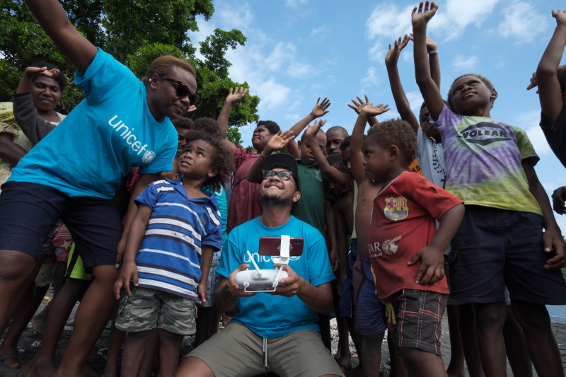 Children in Vanuatu watch a drone operator